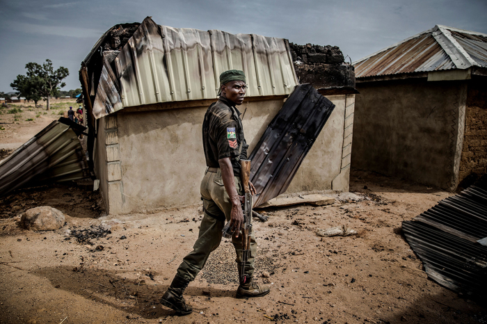 Un policier nigérian patrouille dans une zone de maisons détruites et incendiées après une récente attaque peule dans le village d'agriculteurs Adara d'Angwan Aku, dans l'État de Kaduna, au Nigeria, le 14 avril 2019.